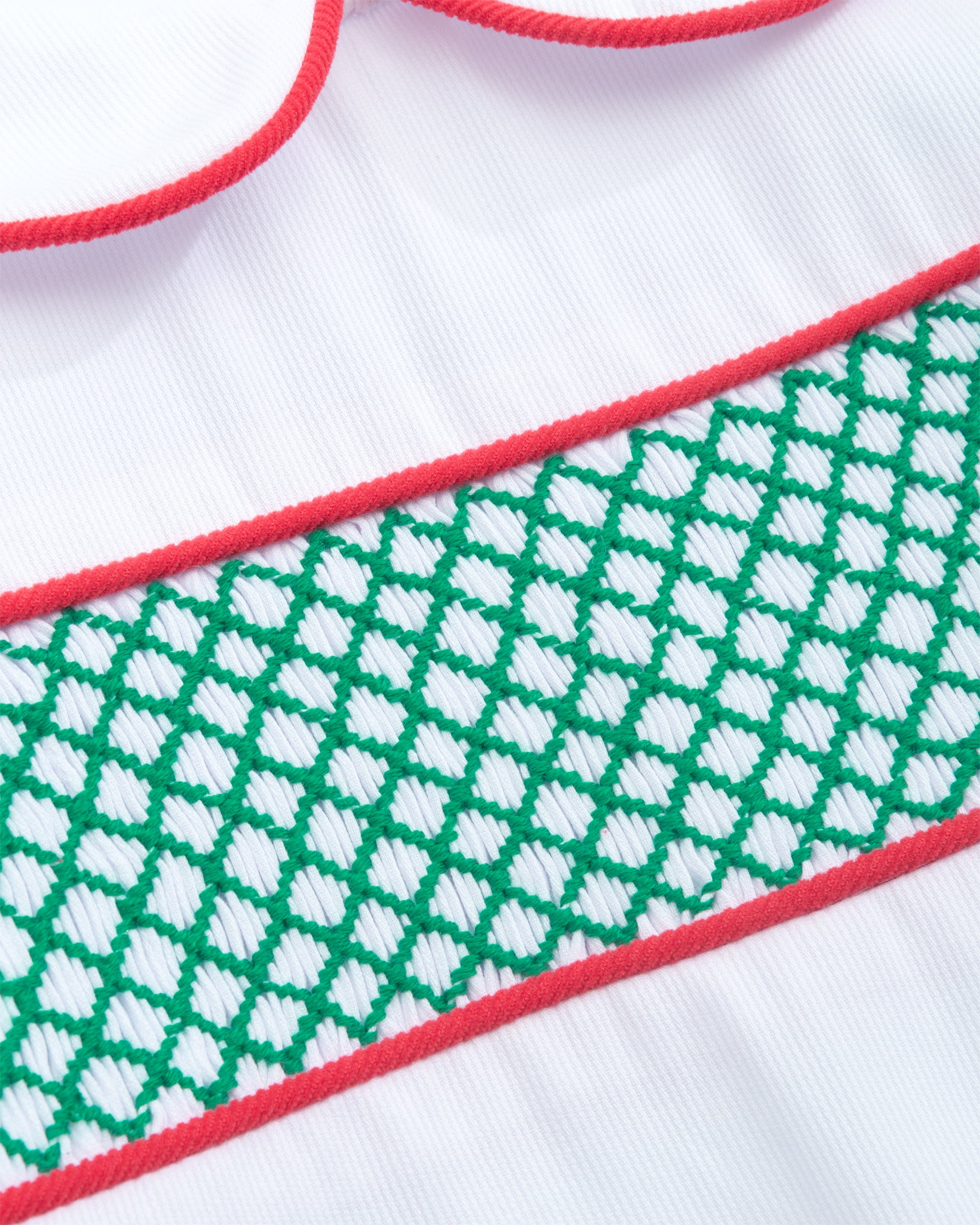 Close-up of a white garment with green and red patterns