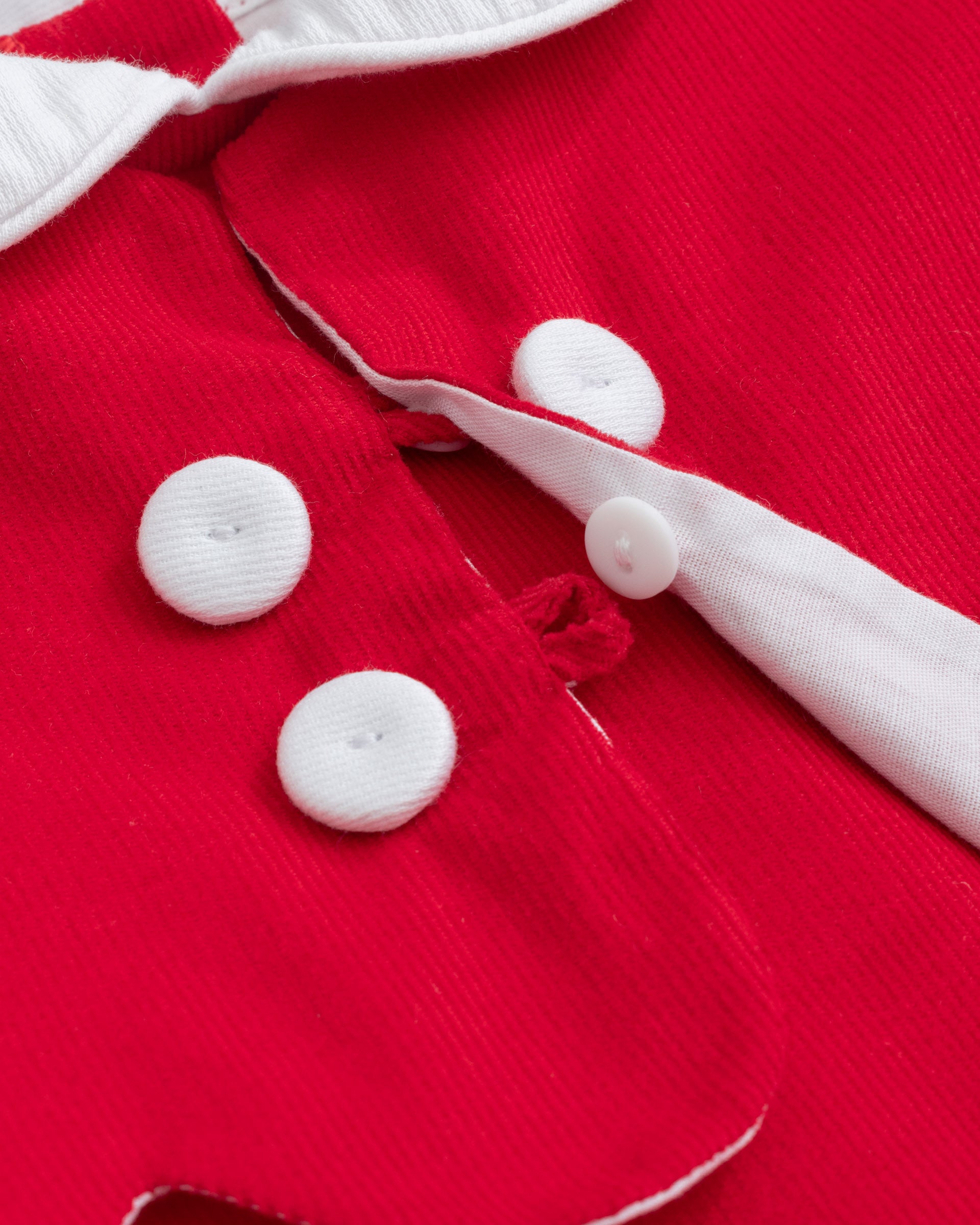 Close-up of a red garment with white buttons and trim