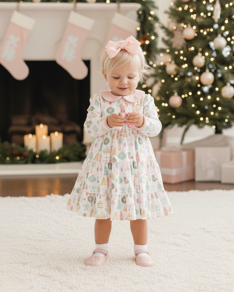 Young girl in a floral dress standing in front of a Christmas tree and fireplace.