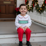 Child sitting on a porch decorated for Christmas with wreaths and lights.