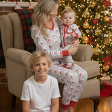 Family in matching pajamas sitting in a living room with a Christmas tree in the background